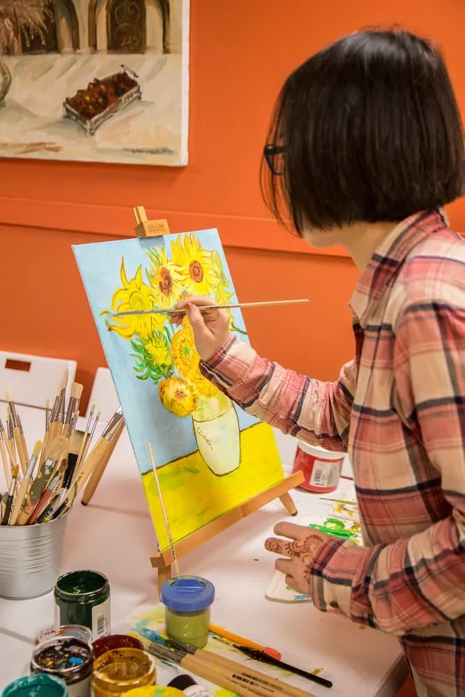 Children's book illustrator painting at an easel in the art studio — creative process at Fairy Tale Publishing